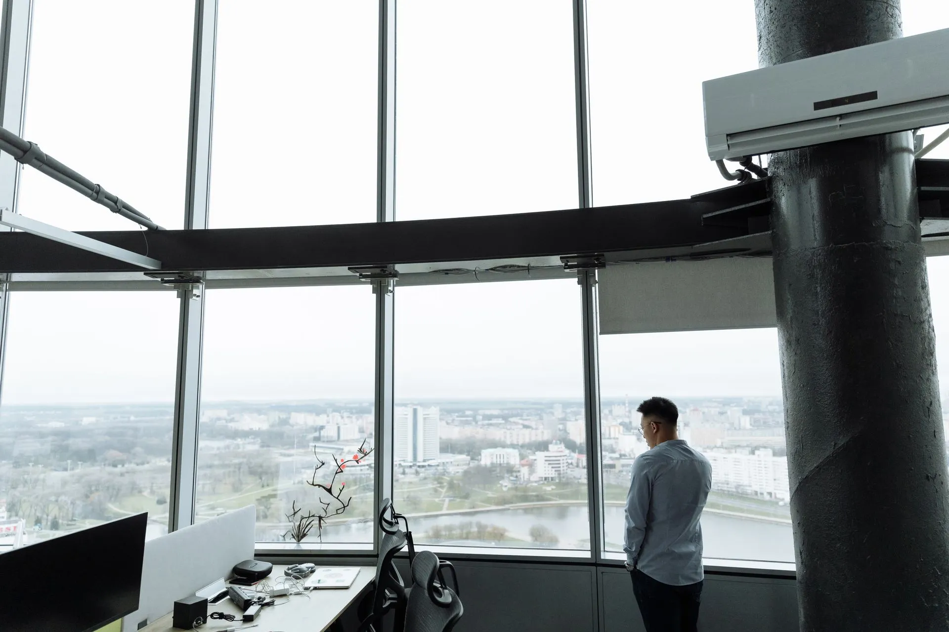 Un homme regarde la ville depuis un bureau vitré en hauteur